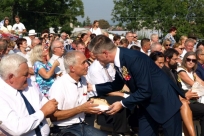 Wójt przekazuje kawałek chleba dozynkowego staroście Wędryni Bogusławowi Raszce